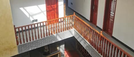 Interior com vários níveis, escada, portas de madeira e tapete vermelho.