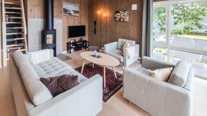 Un salon moderne doté d’une cheminée, d’un téléviseur à écran plat et d’une grande fenêtre offrant une vue sur l’extérieur.
