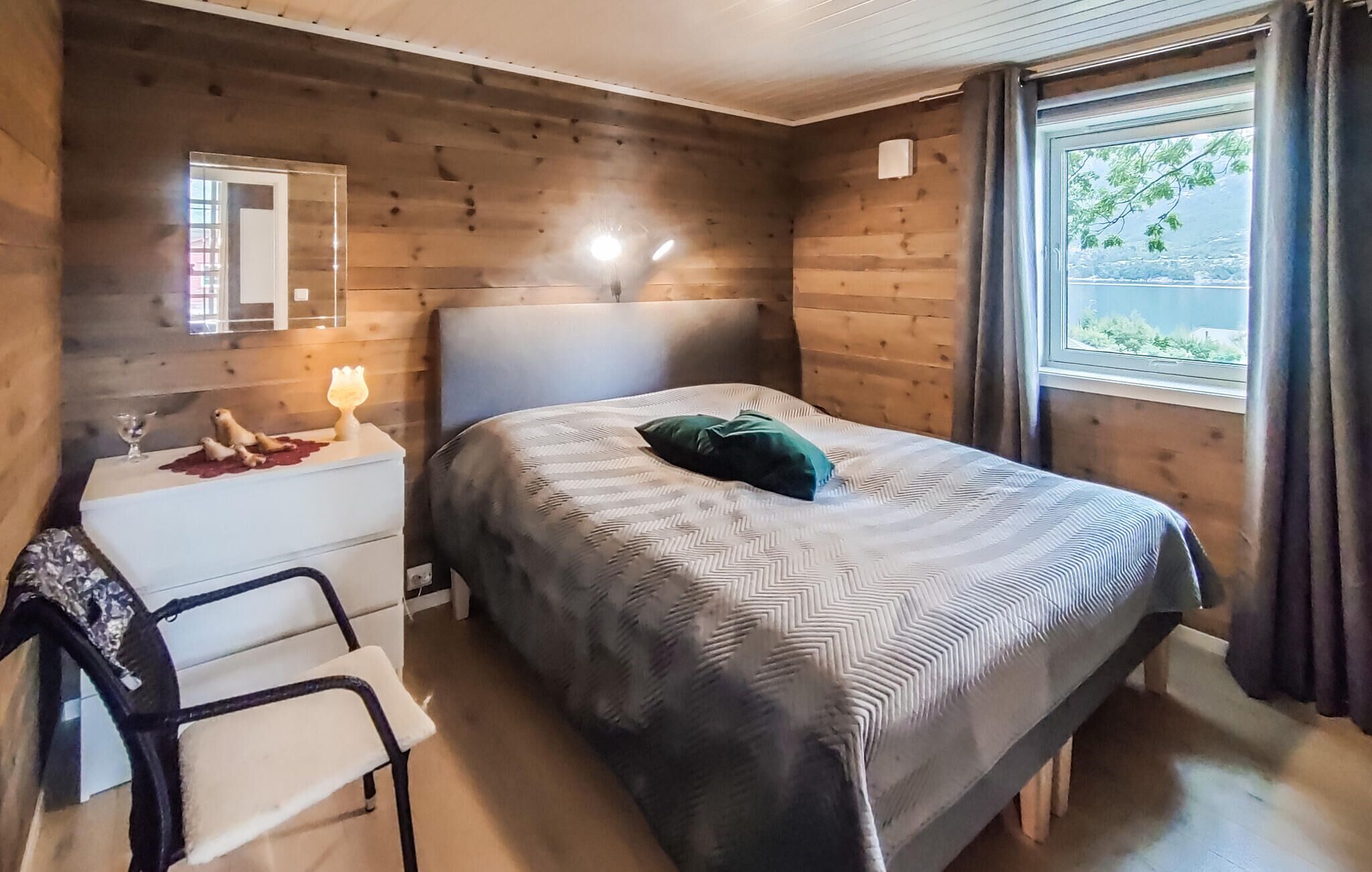 Ein gemütliches Zimmer mit einem Bett, einem kleinen Schreibtisch und einem Fenster mit Vorhängen.