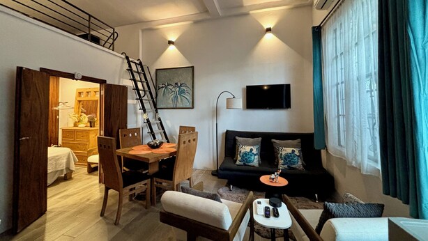 Un salon moderne comprenant un canapé, des fauteuils, une table à manger et une échelle.