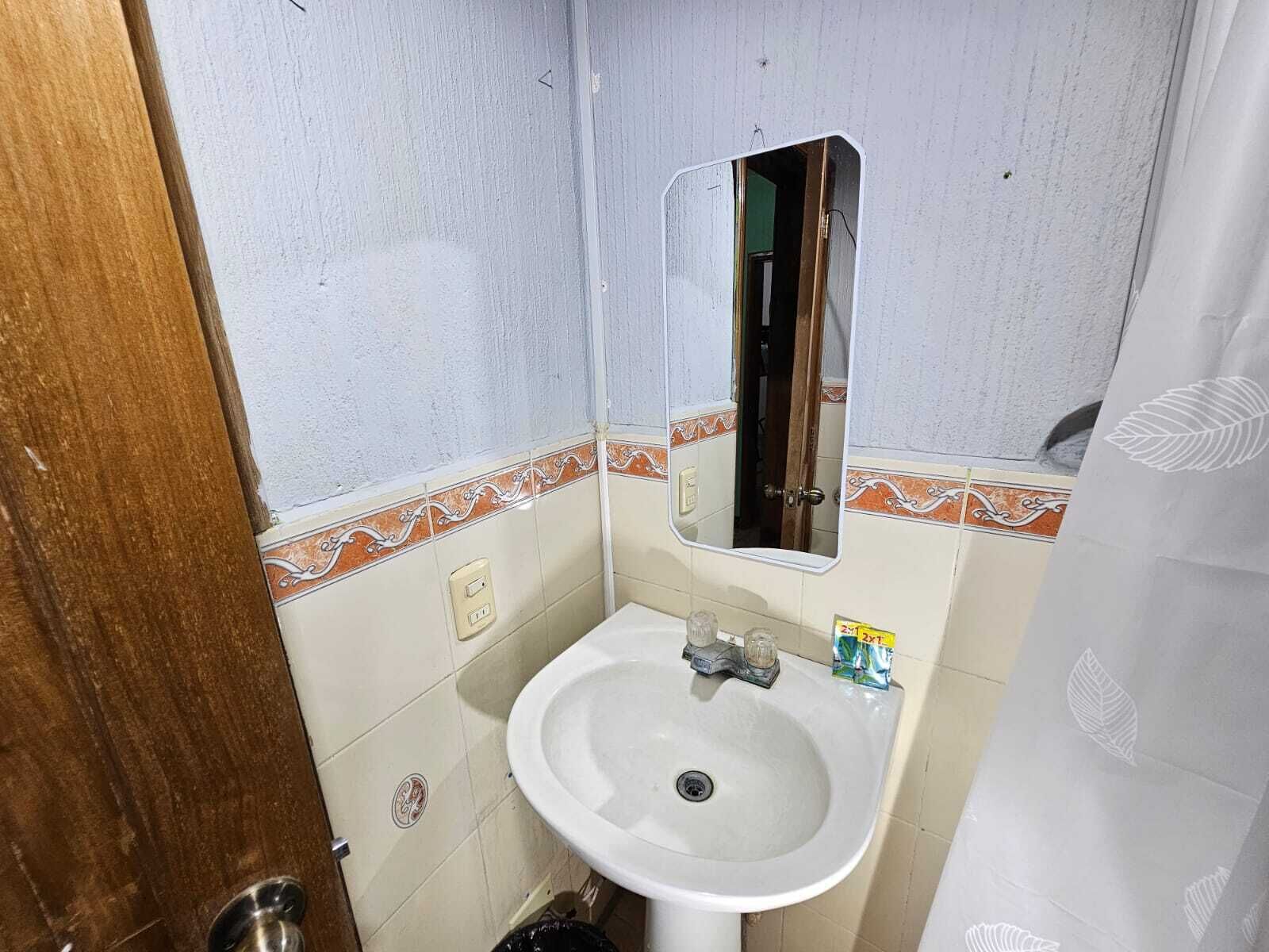 A small bathroom with a white sink, a mirror, and a door.