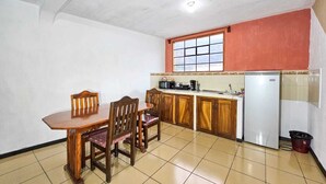 Cocina compacta con mesa y sillas, refrigerador y ventana con vistas.