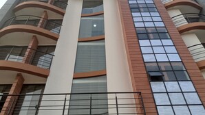 A multi-story building with balconies, large windows, and a central vertical structure.