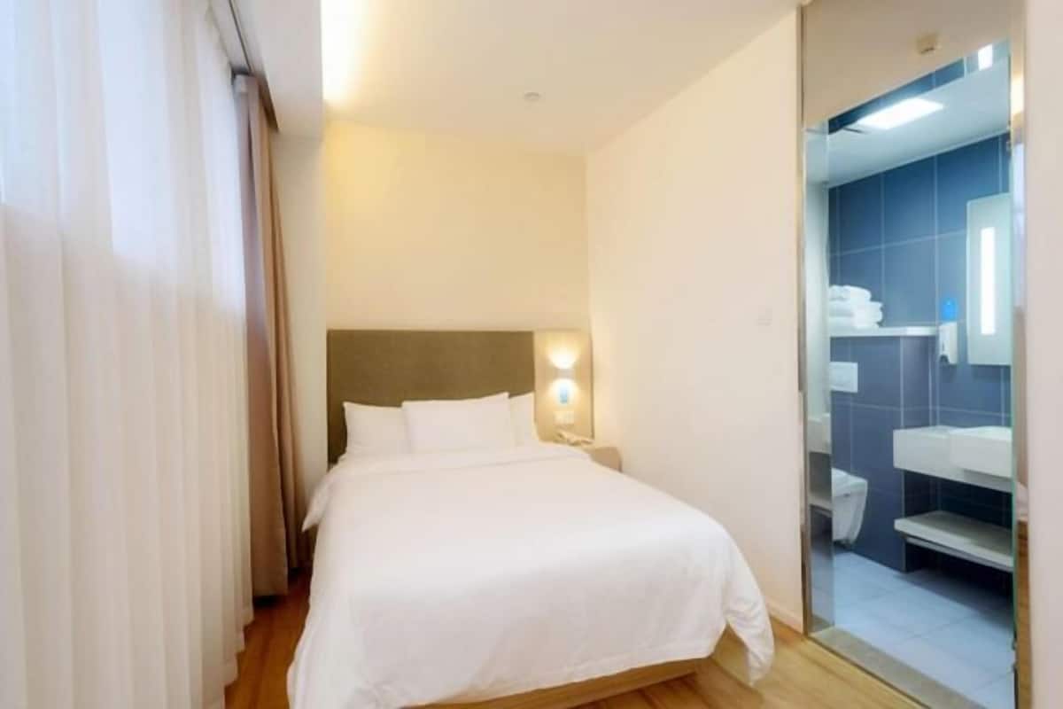 Une chambre d’hôtel avec un lit, une table de chevet, un miroir et une vue sur la salle de bain.