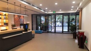 Una moderna zona de recepción con mostrador, asientos y una puerta de vidrio que da al exterior.
