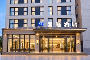 A hotel entrance with a modern facade, large windows, and a sign indicating it is a hotel. - Shengting Hotel (Henan University of Technology Enterprise Base Branch) (Zhengzhou)