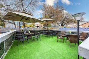 Un espace extérieur aménagé avec des tables et des chaises, entouré d’une pelouse verdoyante, et des parasols pour offrir de l’ombre.