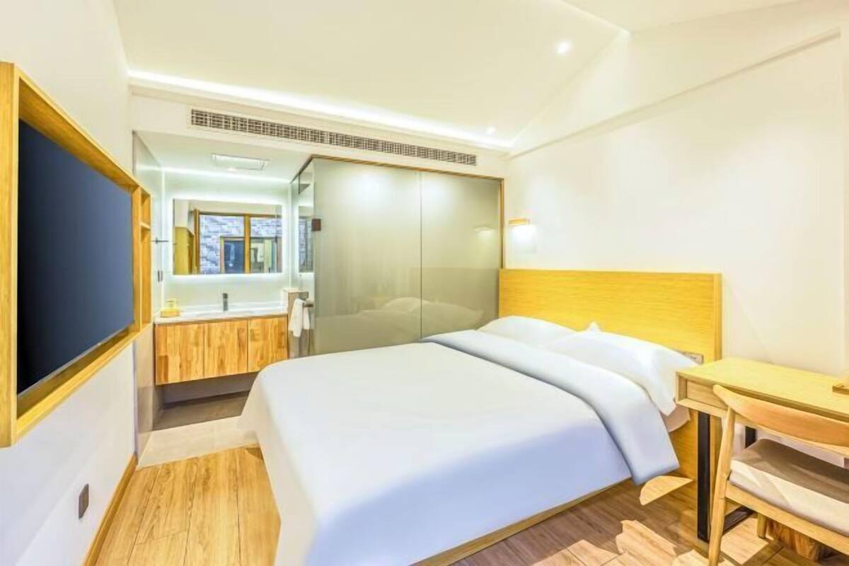 Une chambre d’hôtel avec un lit, un bureau, un miroir et une armoire.