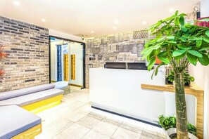 Un espace d’accueil comprenant un comptoir de réception, un coin salon et une plante.