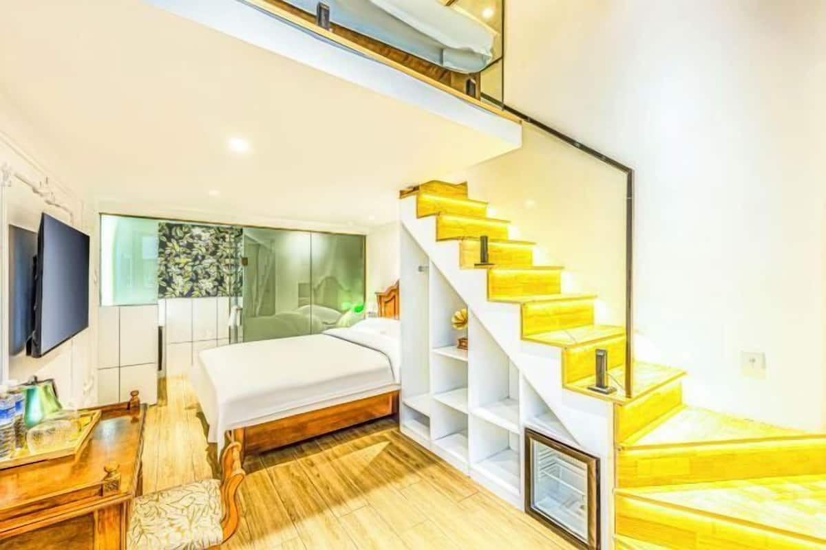 Une chambre moderne avec un lit, un bureau et un escalier dont les marches sont jaunes.