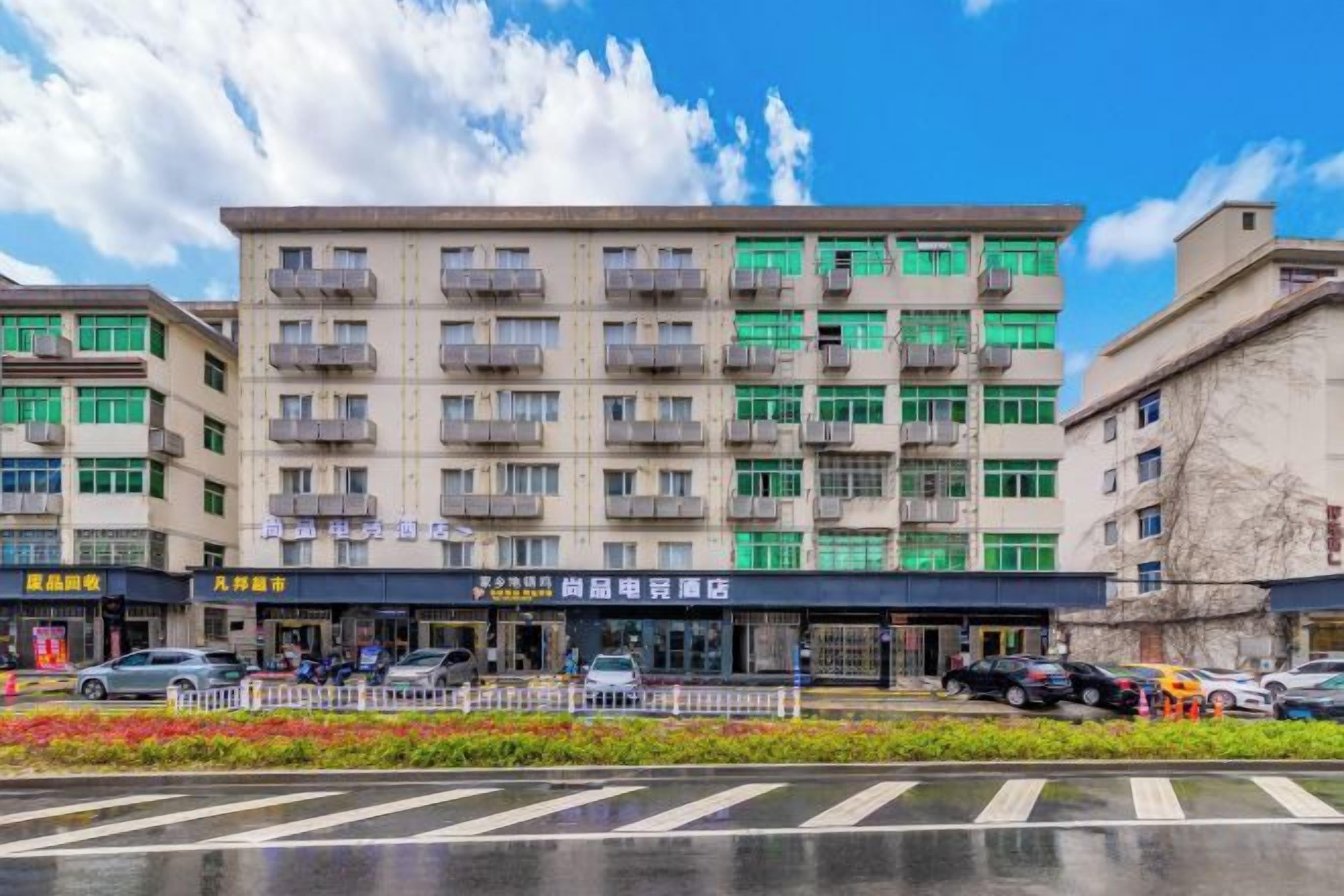 A multi-story building with balconies, a storefront, and a parking area.