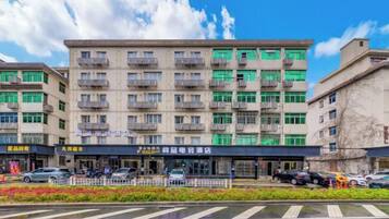 A multi-story building with balconies, a storefront, and a parking area.