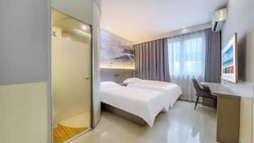 A hotel room with a bed, a desk, a chair, and a shower area.