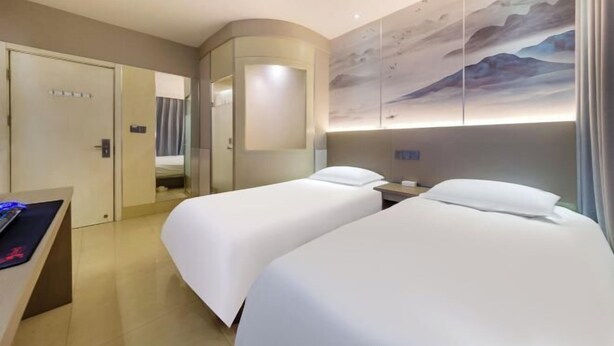 Une chambre d’hôtel avec deux lits, un bureau, un miroir et une œuvre d’art accrochée au mur.