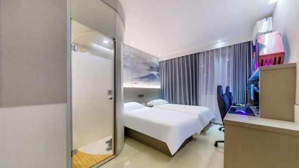 Moderni hotellihuone, jossa on sänky, työpöytä ja tietokone.