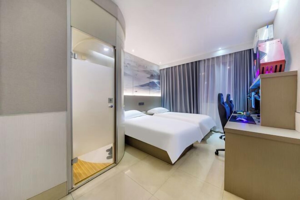 A modern hotel room with a bed, a desk, and a computer.