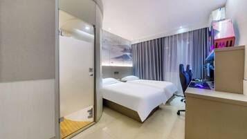 A modern hotel room with a bed, a desk, and a computer.