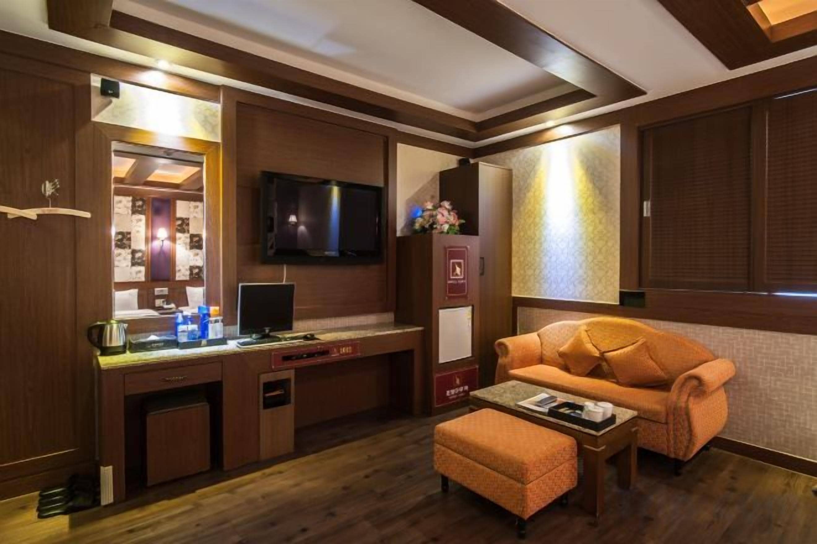 Habitación de hotel con un escritorio de madera, un televisor de pantalla plana, un sofá y una mesita.