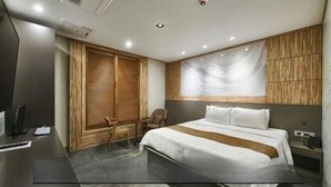 Una habitació d'hotel moderna amb un llit gran, una taula de treball i una cadira.