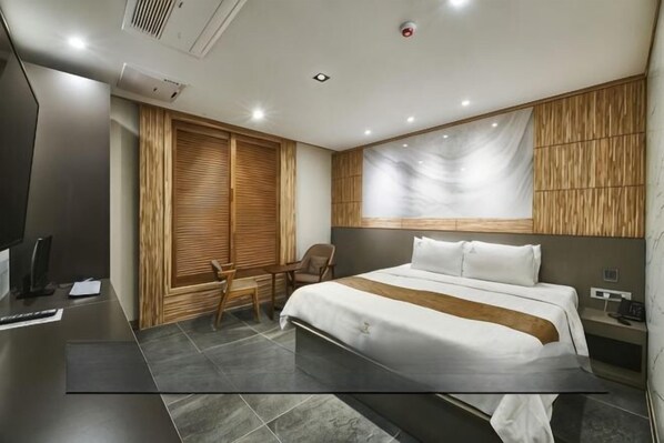 A modern hotel room with a large bed, a desk, and a chair. - Aura Tourist Hotel (Ansan)