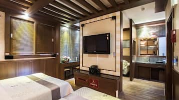 A hotel room with a TV, a bed, a desk, and a bathroom visible through an open door.