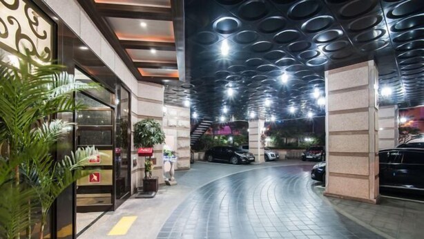 Un vestíbul d'hotel modern amb un camí corbat, una escala i una zona d'aparcament.