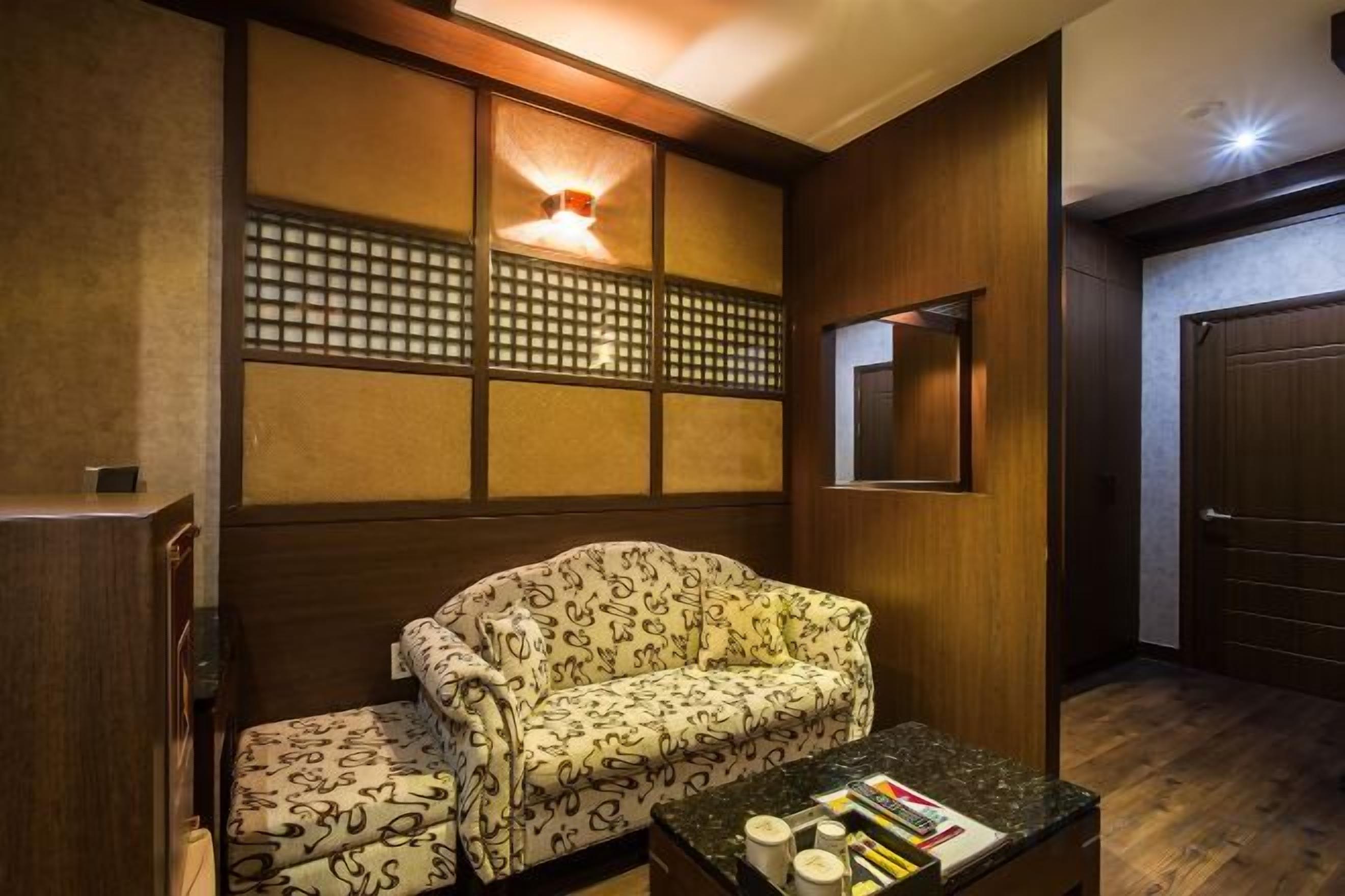 A room with a sofa, a coffee table with books, a wall-mounted light, and a sliding door.
