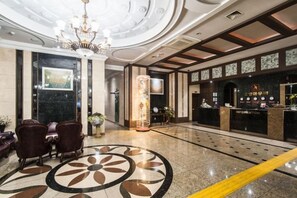 A hotel lobby with a reception desk, seating area, and a decorative floor pattern. - Aura Tourist Hotel (Ansan)