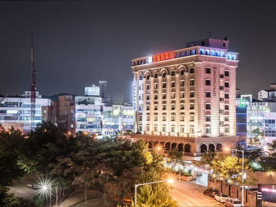 Un hotel de varios pisos con un letrero rojo llamativo en la parte superior, rodeado de otros edificios.