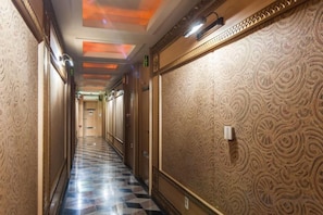 A hotel corridor with patterned walls, a checkered floor, and a ceiling with recessed lighting. - Aura Tourist Hotel (Ansan)