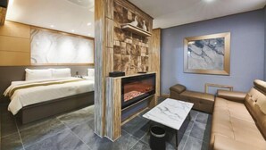 Habitació d'hotel amb llit, una llar de foc, un sofà i un paviment de marbre.