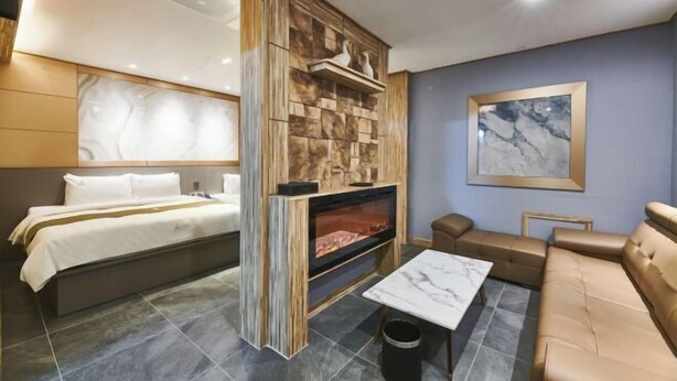 A hotel room with a bed, a fireplace, a sofa, and a marble-tiled floor. - Aura Tourist Hotel (Ansan)