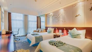 A hotel room with two beds, a desk, a chair, and a large window.