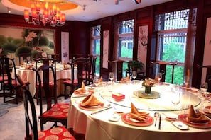 A dining area with round tables, chairs, and a chandelier. - Yangfeng Yiju Hotel (Beijing)