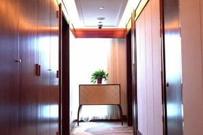 A hallway with wooden doors, a potted plant on a stand, and a ceiling light. - Yangfeng Yiju Hotel (Beijing)