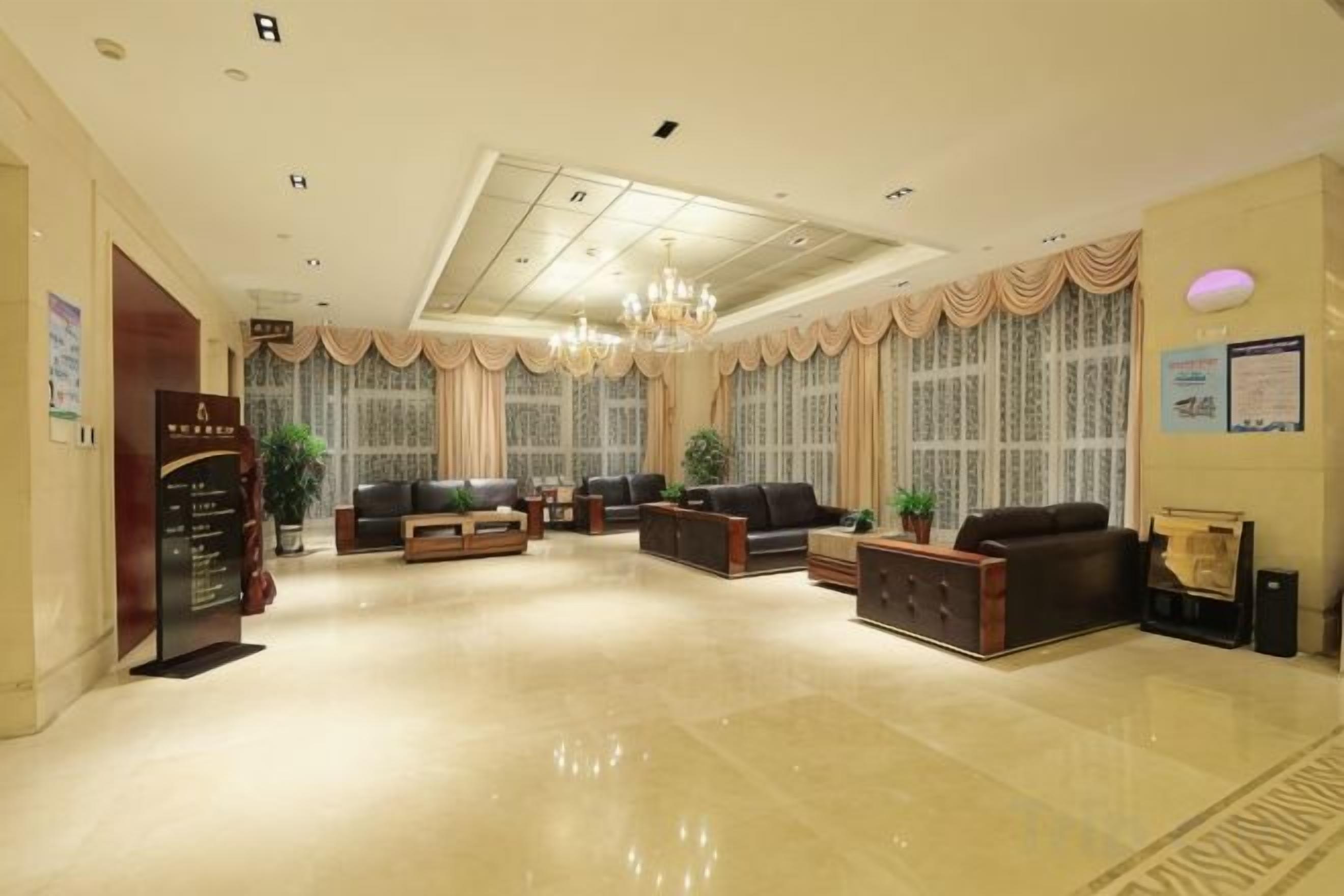 Um hall amplo com teto alto, lustres e um balcão de recepção.