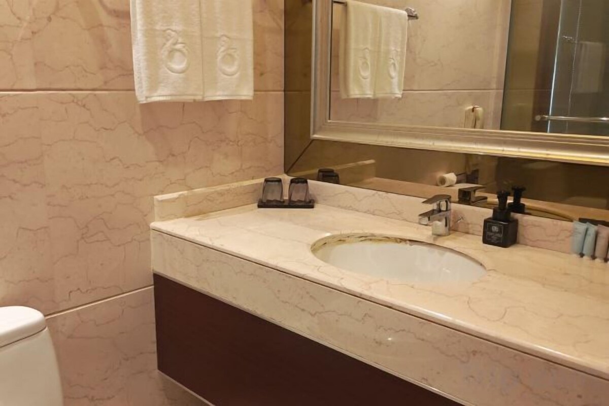 A bathroom with a marble sink, a mirror, and a towel rack.
