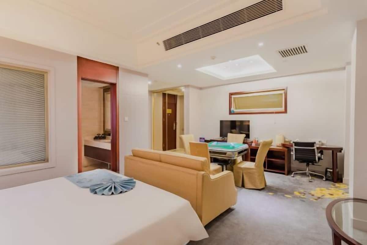 A hotel room with a bed, a desk, a chair, and a small table.