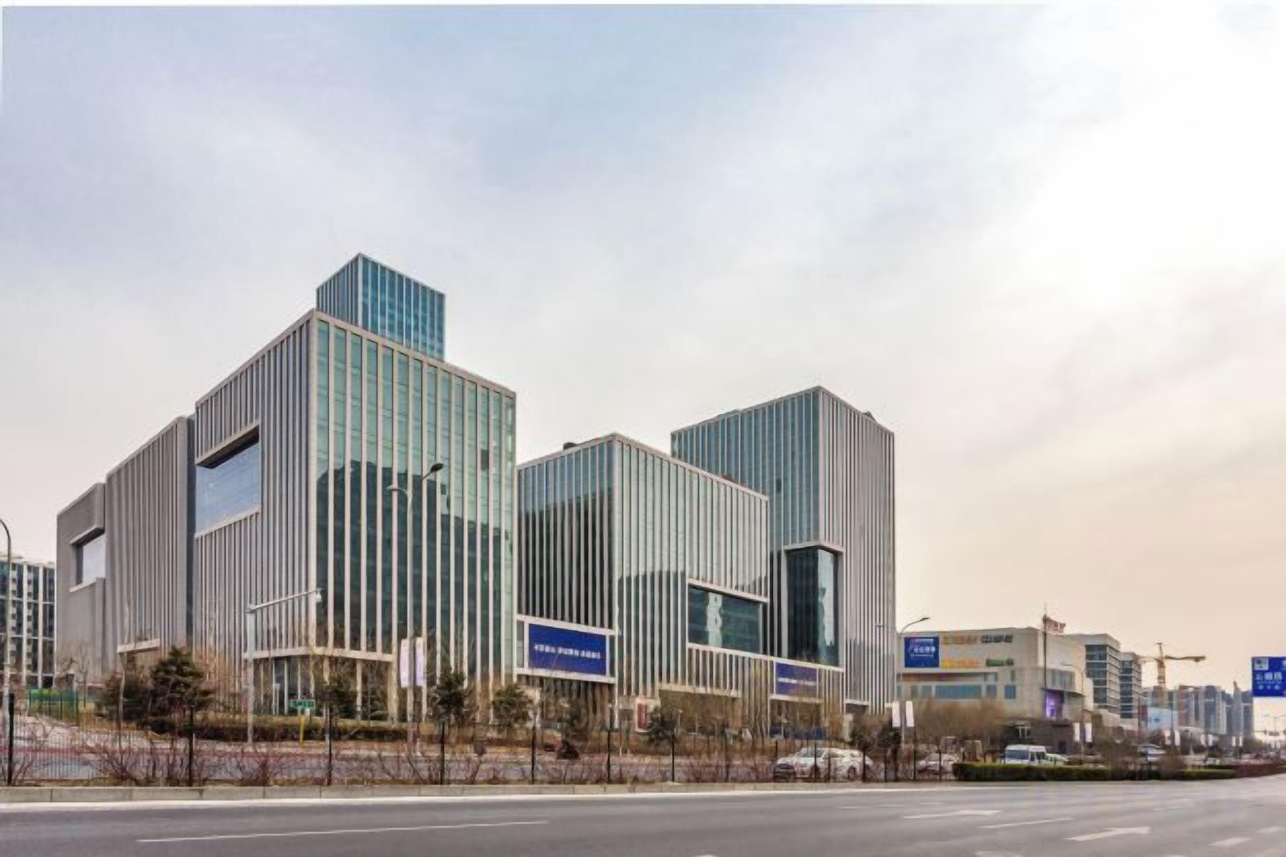 A modern building with a glass facade, multiple floors, and a flat roof.