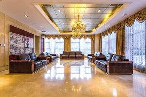 A spacious lobby with leather sofas, a chandelier, and large windows with curtains. - Yangfeng Yiju Hotel (Beijing)