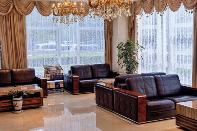 A spacious living room with leather sofas, a coffee table, and a chandelier.