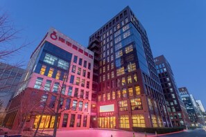 A multi-story building with a modern architectural design, featuring large windows and a prominent signage. - Yangfeng Yiju Hotel (Beijing)