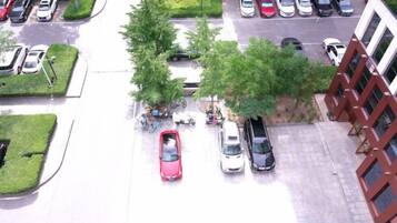 A parking lot with cars, trees, and a building with a red facade.