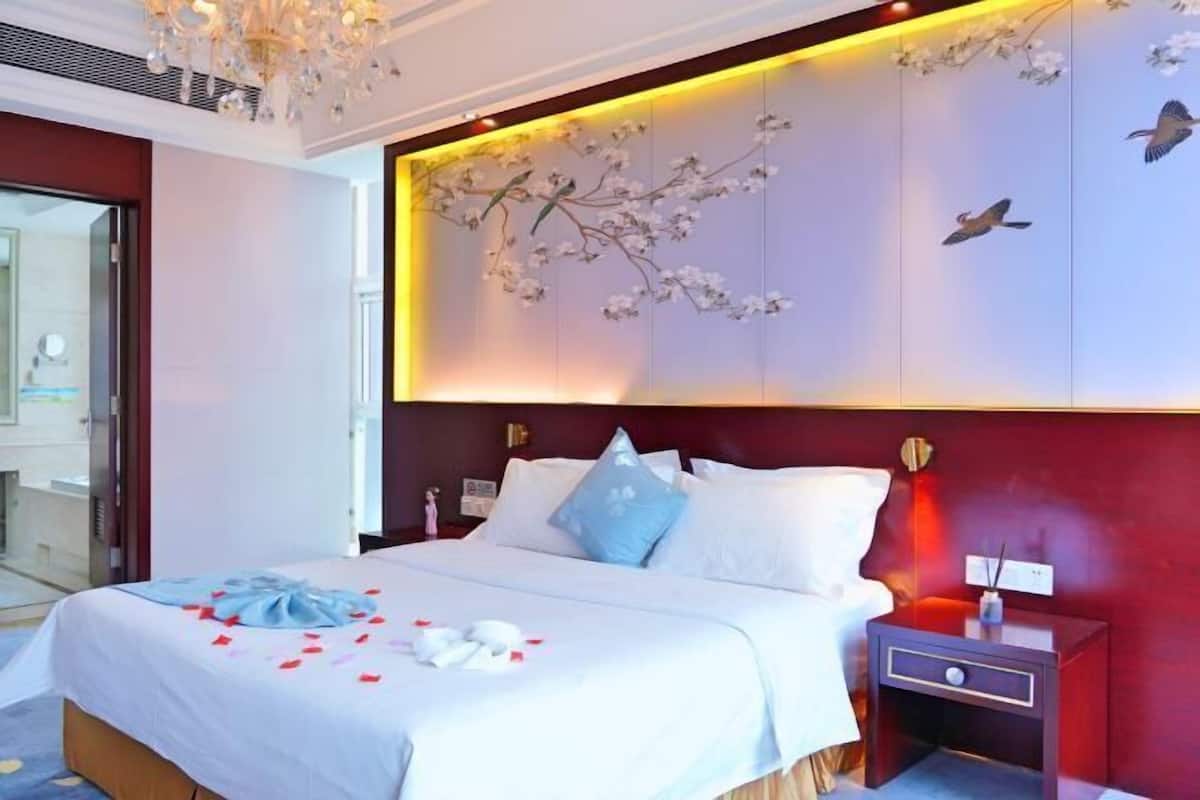 A hotel room with a bed, nightstand, and a wall with floral and bird decorations.