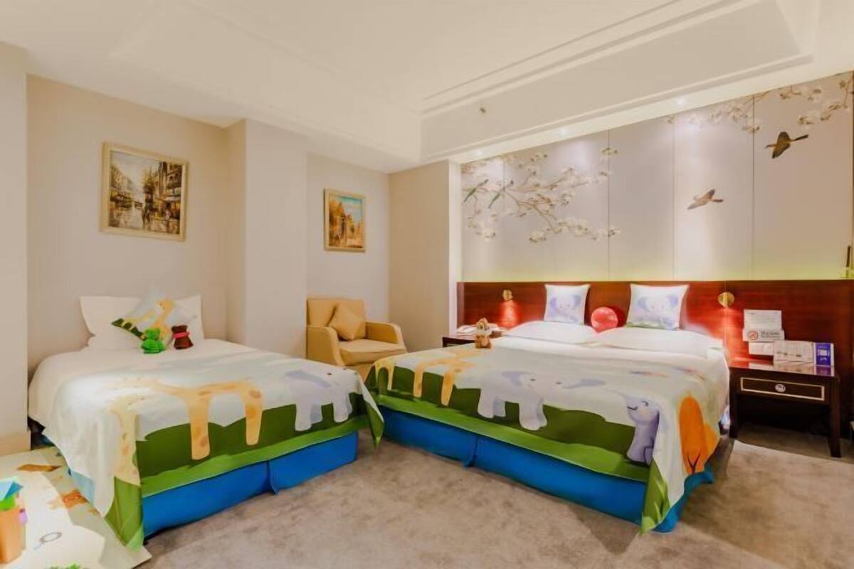 A hotel room with two beds, a sofa, and artwork on the walls.