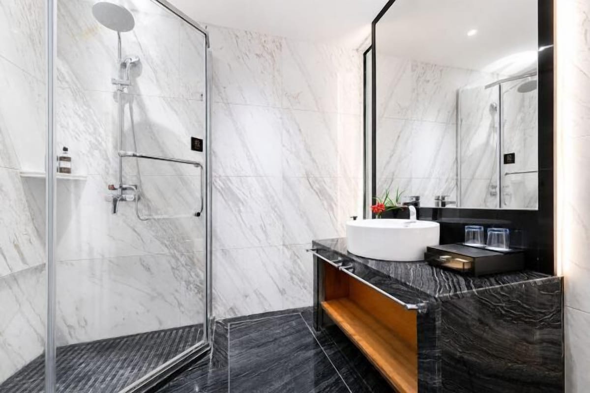 Une salle de bain moderne avec une douche à parois de verre, un lavabo blanc et un meuble-lavabo en bois.