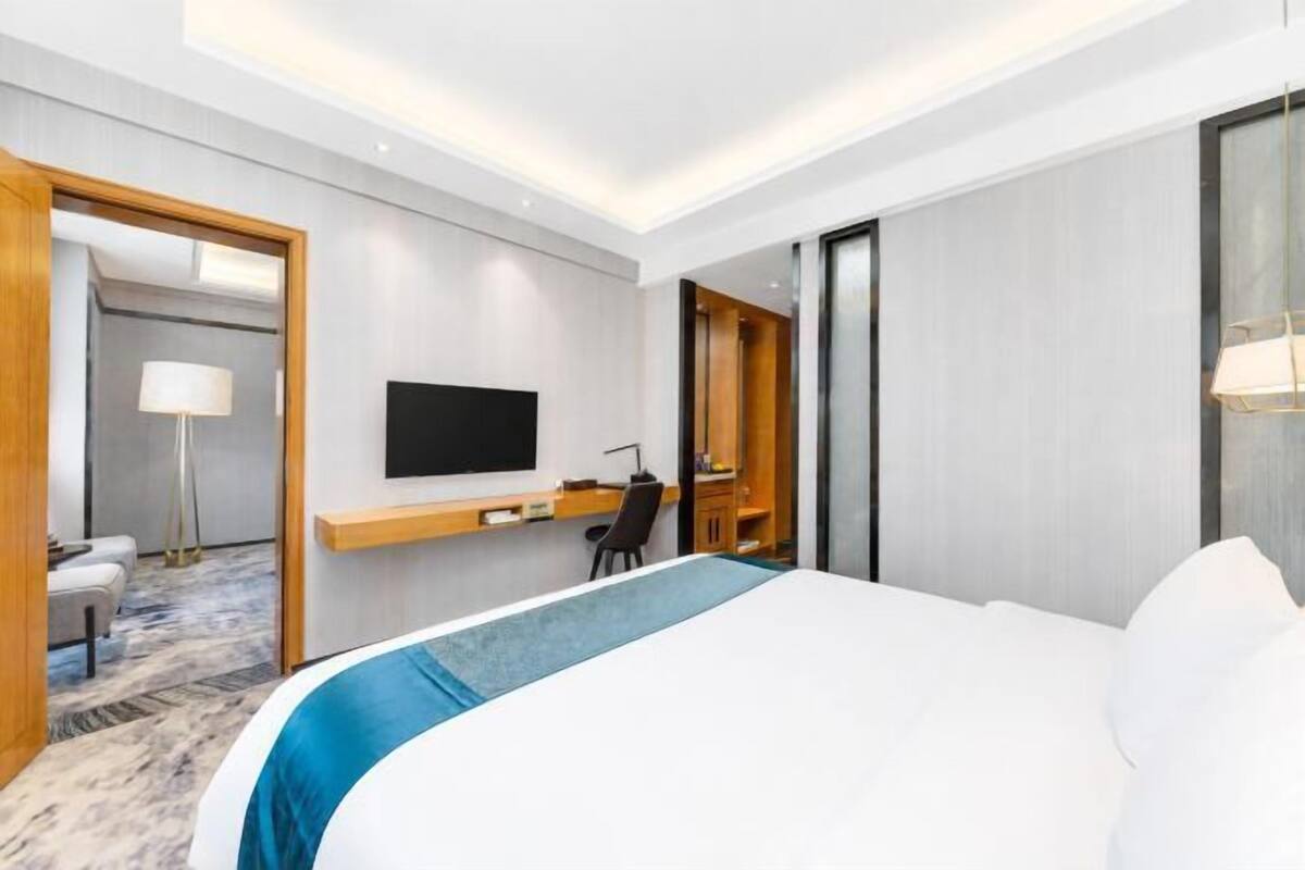Une chambre d’hôtel avec un lit, un bureau, une télévision et un miroir.