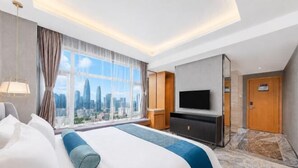 Une chambre d’hôtel avec un grand lit, une télévision, une vue sur la ville et une porte.