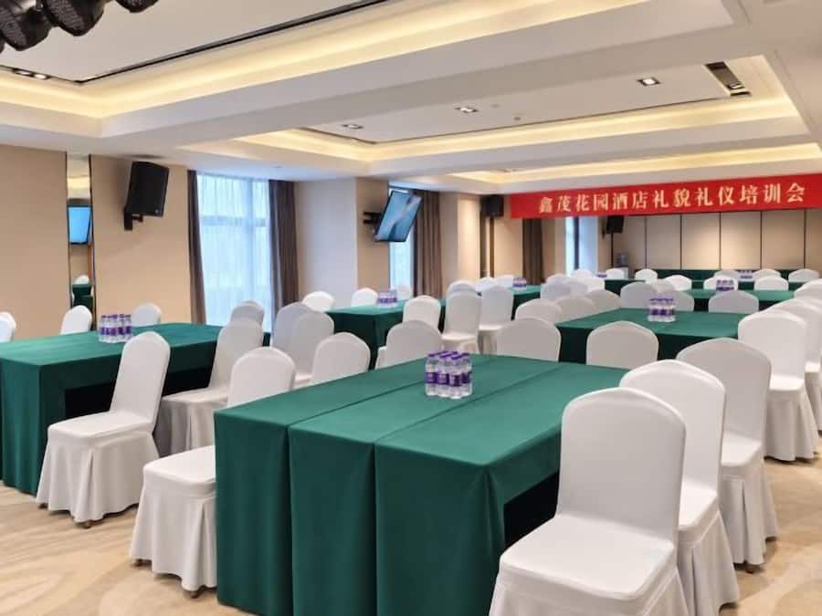 A conference room with multiple tables and chairs, equipped with microphones and screens.