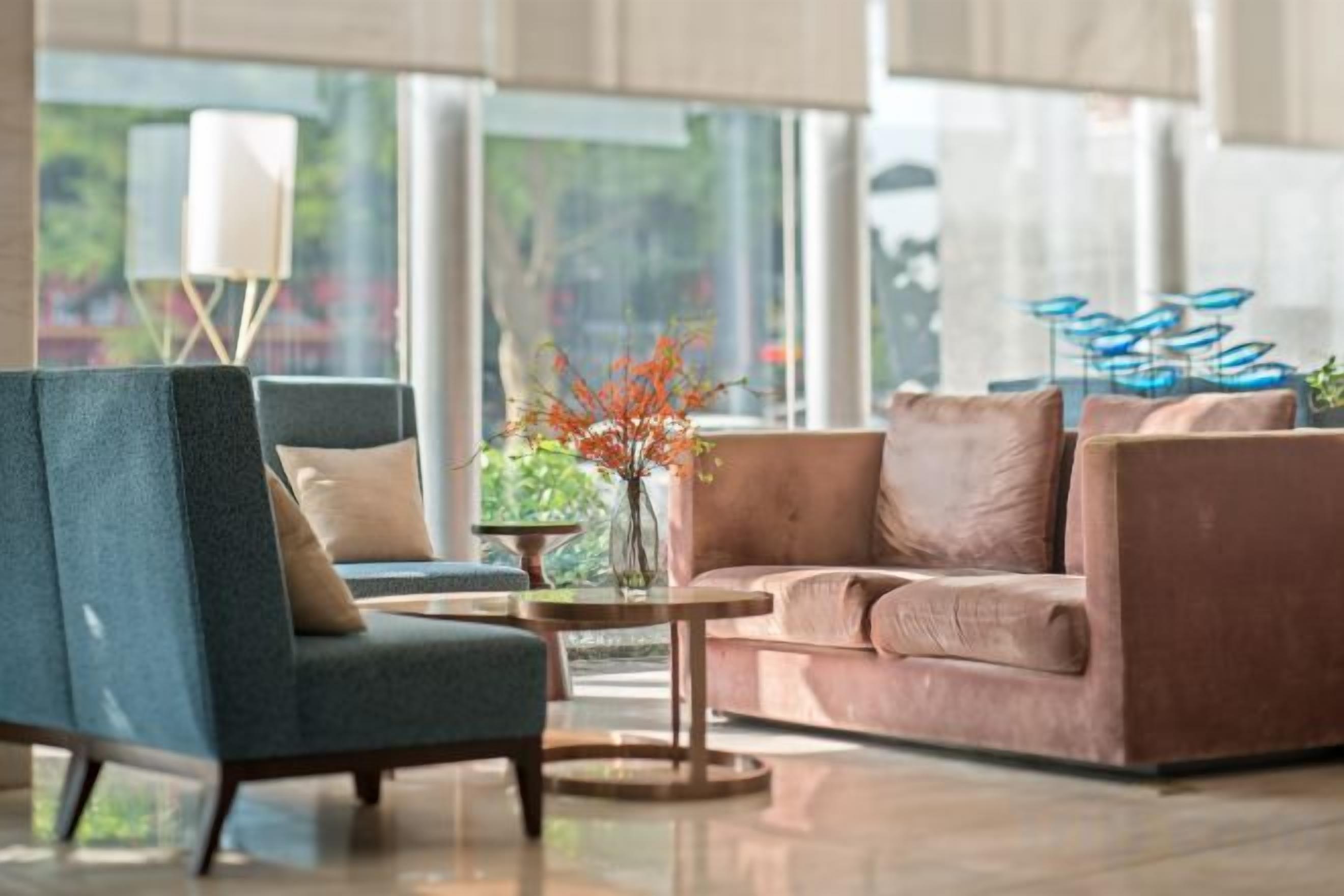 A modern living room with a blue armchair, a brown sofa, and a coffee table with a vase of flowers.